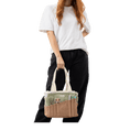 Load image into Gallery viewer, A person is standing against a black background, holding a bag with multiple compartments.