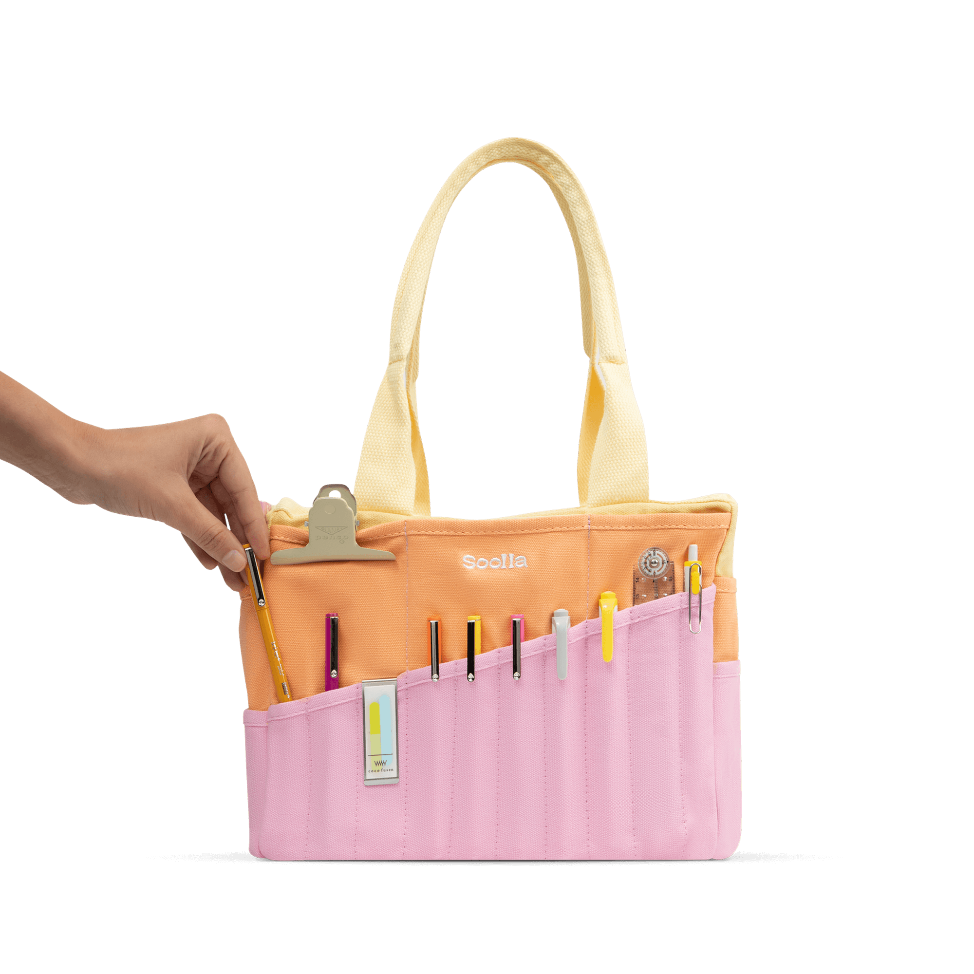 A hand holding a yellow pencil case with various writing utensils and a clip inside, against a black background.